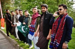 grupo de hombres paquistaníes vestidos con ropa tradicional salwar kameez o kurta con banderas de pakistán. foto