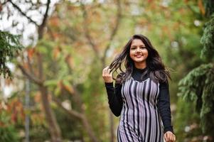 retrato de una joven y hermosa adolescente india o del sur de asia vestida en un parque de otoño en europa. foto