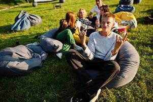 Young multi ethnic group of people watching movie at poof in open air cinema. Close up portrait of funny guy. photo