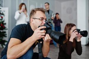 The team of two photographers shooting on studio behind another three workers. Professional photographer on work. Master class. photo