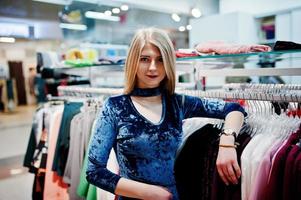 Blonde girl in blue dress in the clothing store boutique. photo