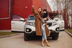 Young mother and child stand near they suv car. Safety driving concept. photo