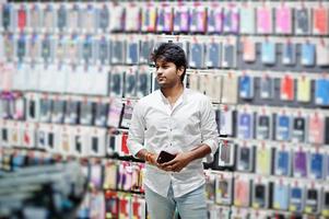 el comprador de un cliente indio en una tienda de teléfonos móviles elige un estuche para su teléfono inteligente. concepto de pueblos y tecnologías del sur de Asia. tienda de celulares foto