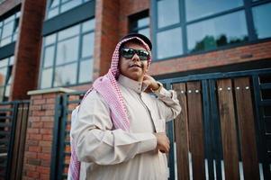 Middle Eastern arab business man posed on street against modern building with sunglasses. photo