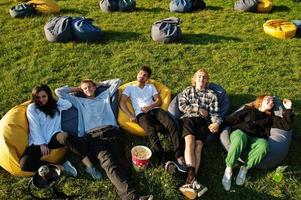 Young multi ethnic group of people watching movie at poof in open air cinema. photo