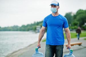 Delivery water man wear protective face medical mask during coronavirus pandemia. photo