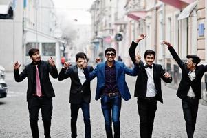 Group of 5 indian students in suits posed outdoor, having fun and dancing. photo