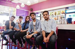 Group of stylish asian friends wear on jeans sitting at chairs against bar in club. photo