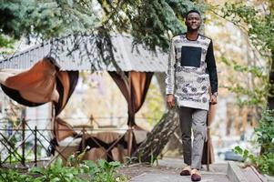 apuesto hombre afroamericano vestido con ropa tradicional en la ciudad moderna. foto