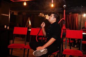 Asian man smoke hookah and having rest at lounge bar. photo