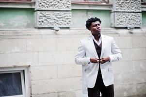 pensativo joven apuesto caballero afroamericano en ropa formal. hombre modelo elegante negro con chaqueta blanca. foto