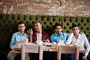 Group of four south asian men's posed at business meeting in cafe. Indians watching tv and cheering for they favorite team. photo