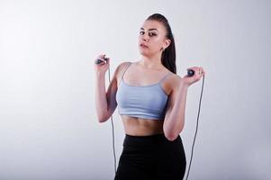 Cheerful attractive young fitness woman in top and black leggings with jump rope isolated over white background. photo