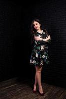 Portrait of a fabulous young woman in floral dress in the dark studio. photo