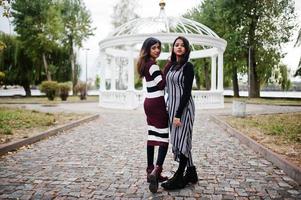 Portrait of two young beautiful indian or south asian teenage girls in dress background white temple arch. photo