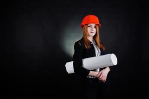 Engineer woman in orange protect helmet with construction paper projekt. photo