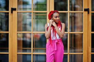 Fashionable african american girl at pink pants and red dreads posed outdoor. photo