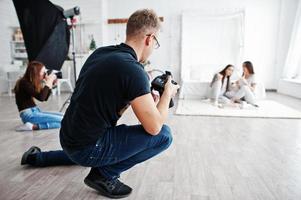 el equipo de dos fotógrafos fotografiando a las gemelas de estudio. fotógrafo profesional en el trabajo. foto