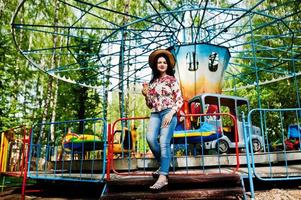 Portrait of brunette girl in pink glasses and hat with ice cream at amusement park. photo