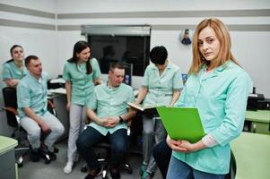 Medical theme .Portrait of female doctor with clipboard against group of doctors meeting in the mri office at diagnostic center in hospital. photo