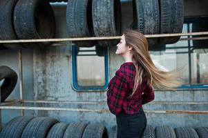 Young hipster girl in checkered shirt at tire fitting zone. photo