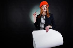 Engineer woman in orange protect helmet with construction paper projekt. photo