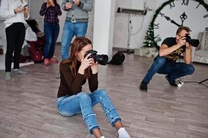 The team of two photographers shooting on studio behind another three workers. Professional photographer on work. photo