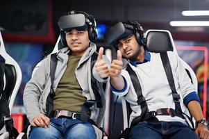 Two young indian people having fun with a new technology of a vr headset at virtual reality simulator. They happy and show thumb up. photo