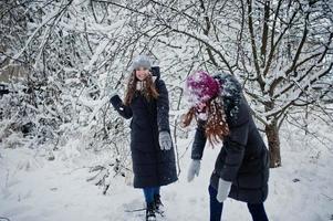 Two funny girls friends having fun at winter snowy day near snow covered trees. photo