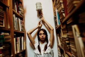 Girl with pigtails in white blouse at old library. photo