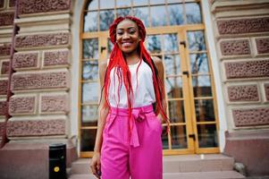 Fashionable african american girl at pink pants and red dreads posed outdoor. photo