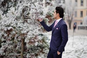 elegante modelo de hombre macho indio con traje y corbata rosa posado en el día de invierno. foto