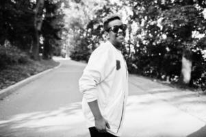 Stylish hipster arab man guy in sunglasses posed outdoor in street at sunset. photo