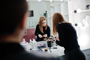 Make up artist work in her beauty visage studio salon. Woman applying by professional make up master. Beauty club concept. photo