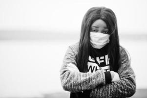 niña africana en el parque con máscaras médicas para protegerse de infecciones y enfermedades cuarentena del virus del coronavirus. foto