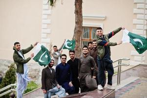 grupo de hombres paquistaníes vestidos con ropa tradicional salwar kameez o kurta con banderas de pakistán. foto