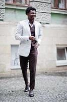 pensativo joven apuesto caballero afroamericano en ropa formal. hombre modelo elegante negro con chaqueta blanca. foto