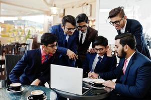 proceso colaborativo de hombres de negocios indios durante una reunión de lluvia de ideas en la oficina. equipo diverso de jóvenes vestidos con trajes que cooperan en el desarrollo de un proyecto común. foto