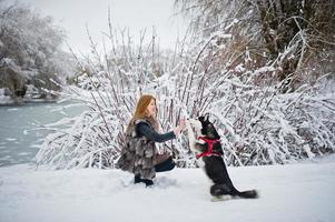 chica pelirroja caminando en el parque con perro husky en día de invierno. foto