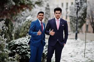 Two elegant indian fashionable mans model on suit posed at winter day and show thumbs up. photo