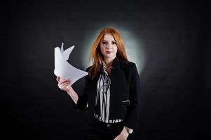 Portrait of a redheaded businesswoman in striped blouse and jacket throwing the paper away. photo