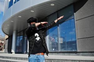 Beard asian man in casual wear posing against new modern building and show dab. photo