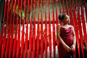 Portrait of a beautiful natural young African woman with afro hair. Black model in red silk dress. photo