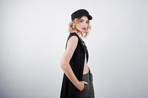 Studio portrait of blonde girl in black wear and cap against white background. photo