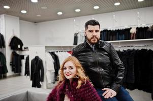 Elegance blonde girl in fur coat and stylish turkish man at the store of fur coats and leather jackets. photo