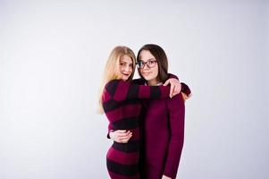 Portrait of two female friends in cherry dresses posing in the studio. photo