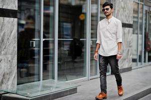 Stylish indian model man in casual clothes and sunglasses posed outdoor at street of India. photo