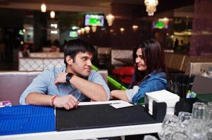 Stylish asian couple wear on jeans sitting on chair at bar in club. photo