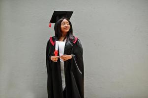 joven estudiante afroamericana con diploma posa al aire libre. foto