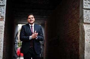 Stylish indian businessman in formal wear standing in tonel and rubs his hands. photo